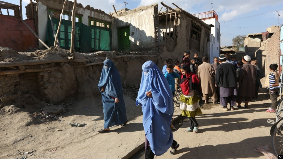 Beberapa perempuan Afghanistan berjalan melewati rumah-rumah yang hancur akibat gempa diKabul, Afghanistan (26/10).