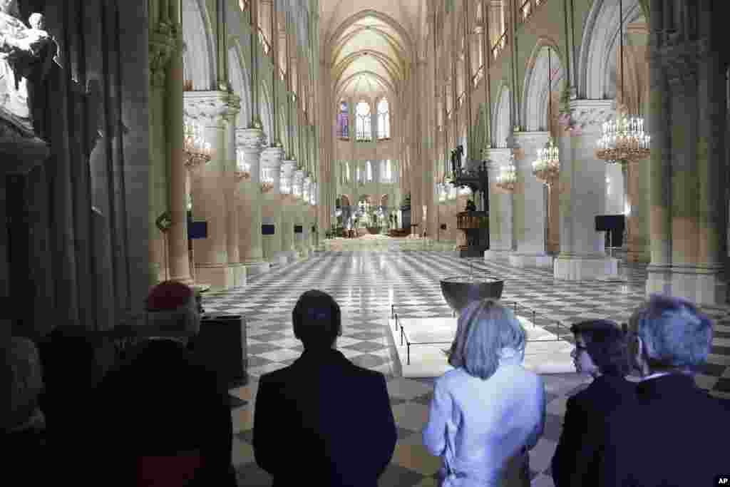 French President Emmanuel Macron, center left, and his wife Brigitte Macron, third right, visit the restored interiors of Notre-Dame Cathedral in Paris. 