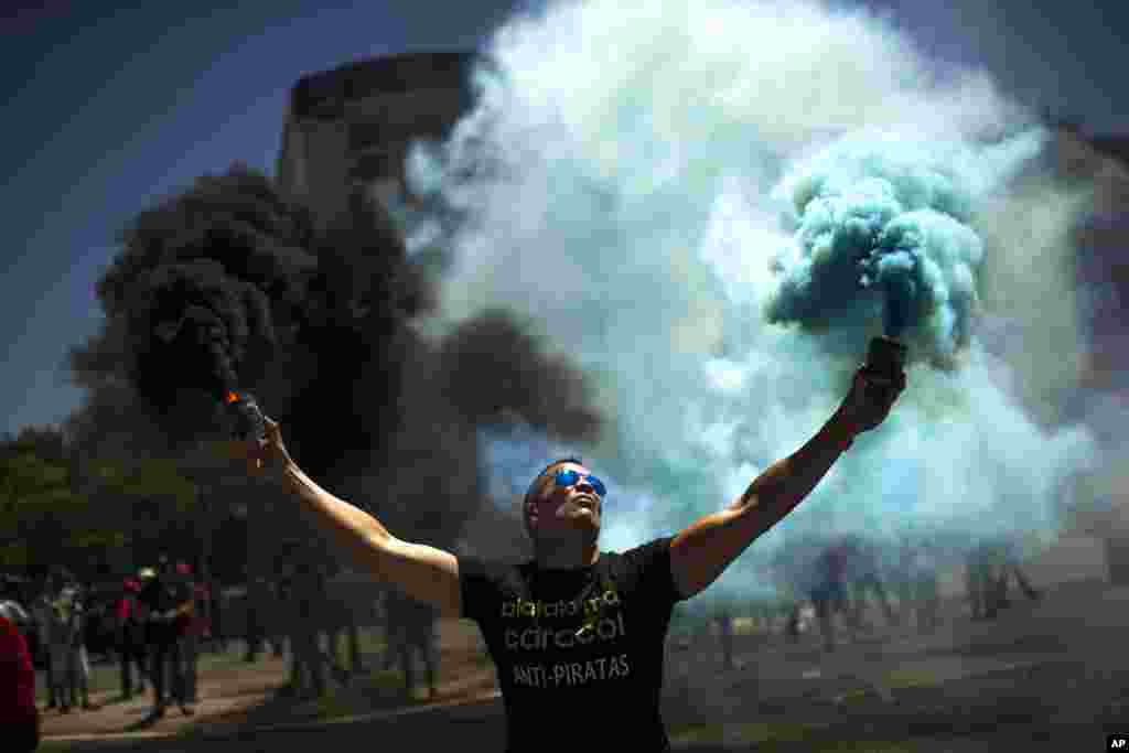 A man holds smoke bombs during a protest by Spanish taxi drivers unions in Madrid. They called for a 24-hour strike to protest the increase in cars run by private companies offering cheaper, mobile ride-hailing services..