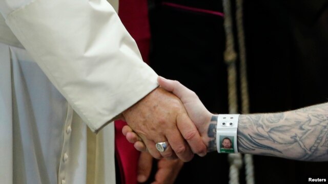 El papa da la mano a un presidiario en una cárcel de Filadelfia.
