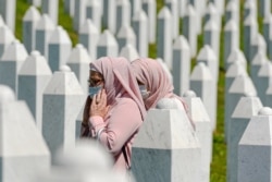Women walk between grave stones in Potocari, near Srebrenica, Bosnia, July 11, 2020.