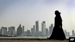 FILE - In this May 14, 2010 file photo, a Qatari woman walks in front of the city skyline in Doha, Qatar.