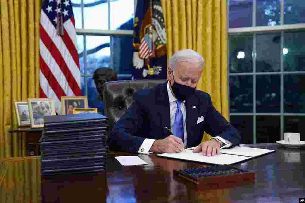 President Joe Biden signs his first executive order in the Oval Office of the White House, Jan. 20, 2021, in Washington.&#160;