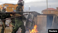 Riot police walk past a bonfire lit by supporters of Kenya's Prime Minister Raila Odinga, the defeated presidential candidate, after the Supreme Court ruling, in the western town of Kisumu, Kenya, March 30, 2013.