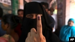An Indian Muslim woman displays the indelible ink mark on her finger after casting her vote, outside a polling station in Chennai, India, April 18, 2019. 