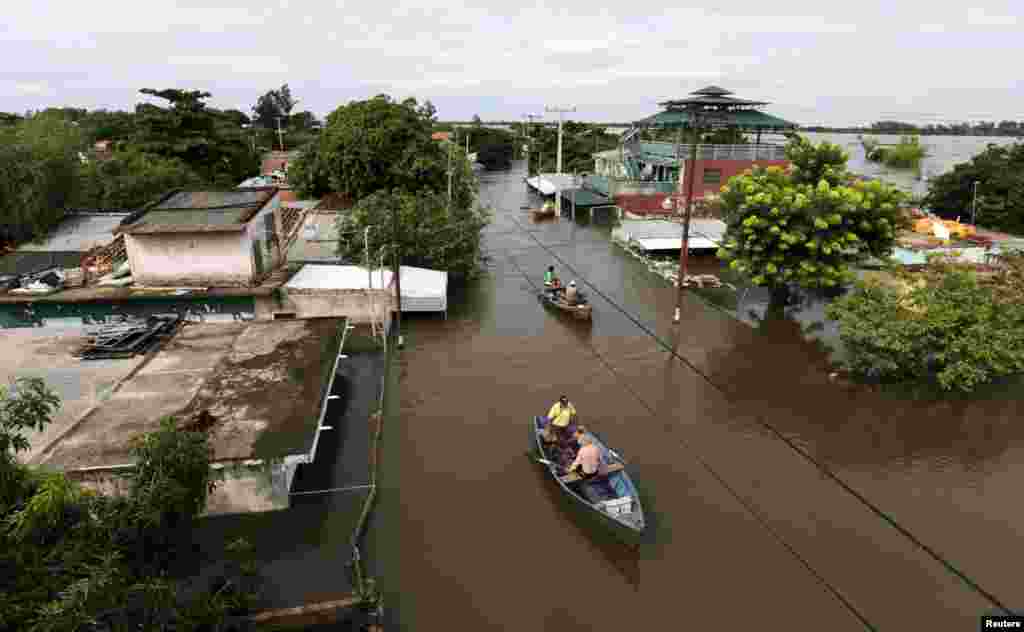 Men travel on a boat near flood-affected houses in Asuncion, Paraguay.&nbsp;More than 100,000 people had to evacuate from their homes in the bordering areas of Paraguay, Uruguay, Brazil and Argentina due to severe flooding in the wake of heavy summer rains brought on by El Niño, authorities said.