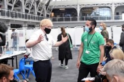 Perdana Menteri Inggris Boris Johnson berbincang dengan sejumlah warga saat mengunjungi pusat vaksinasi COVID-19 di Business Design Centre di Islington, London, Inggris, 18 Mei 2021. (Foto: Jeremy Selwyn/Pool via Reuters)