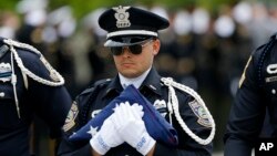 FILE - A member of a police honor guard carries an American flag after funeral services for Baton Rouge Police Officer Matthew Gerald at the Healing Place Church in Baton Rouge, La., July 22, 2016. 