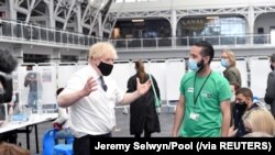 Perdana Menteri Inggris Boris Johnson berbincang dengan sejumlah warga saat mengunjungi pusat vaksinasi COVID-19 di Business Design Centre di Islington, London, Inggris, 18 Mei 2021. (Foto: Jeremy Selwyn/Pool via Reuters) 