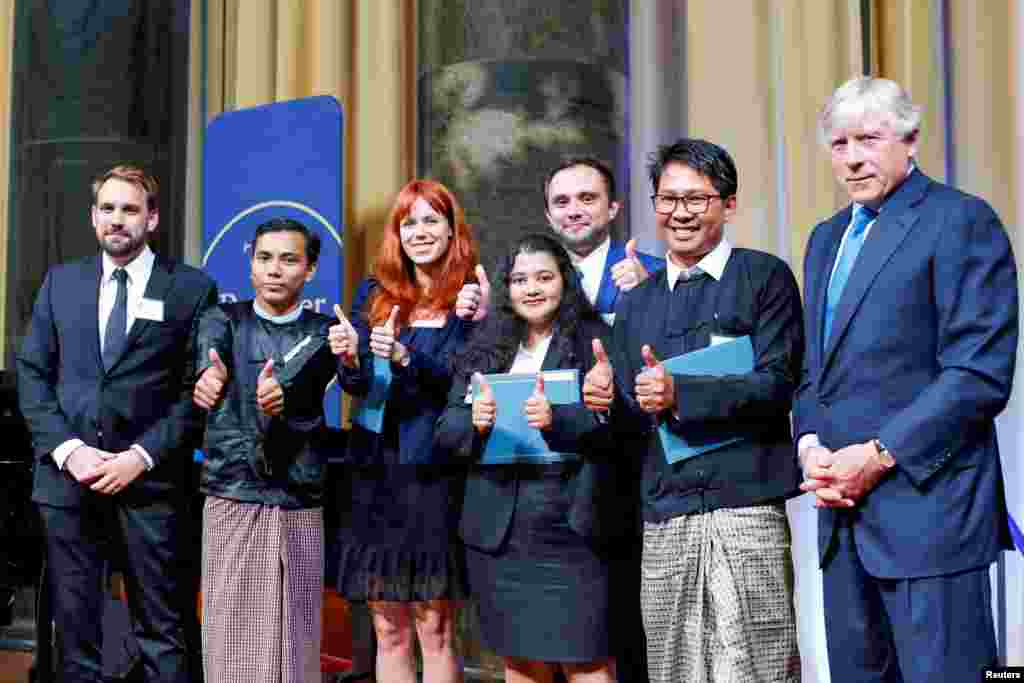 From left to right, Reuters Pulitzer winners for International Reporting: Simon Lews, Kyaw Soe Oo, Poppy McPherson, Shoon Naing, Anthony Slodkoski, Wa Lone, and Columbia University president Lee Bollinger, inside Low Library at Columbia University in New York, May 28, 2019.