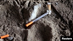 A discarded syringe sits in the dirt with other debris under a highway overpass where drug users are known to congregate in Everett, Washington, Feb. 16, 2017.