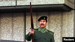 ທ່ານ Saddam Hussein ຍິງປືນຂຶ້ນຟ້າ ໃນຂະນະທີ່ທ່ານຄຳນັບ ພວກອາສາສະໝັກອີຣັກ ທີ່ຈະສູ້ລົບກັບຊາວປາແລສໄຕນ໌ຕໍ່ຕ້ານ ອິສຣາແອລ.