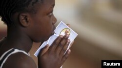 A child holds a prayer paper with the photo of Pope Francis during a special mass at St. Joseph the Worker Catholic Parish within Kangemi, a slum that is home to 650,000 people in Kenya's capital Nairobi, Nov. 22, 2015.