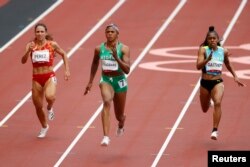 FILE - Blessing Okagbare of Nigeria, center, competes in round 1 of the Women's 100m at the Tokyo Olympics at Olympic Stadium, Tokyo, Japan, July 30, 2021.