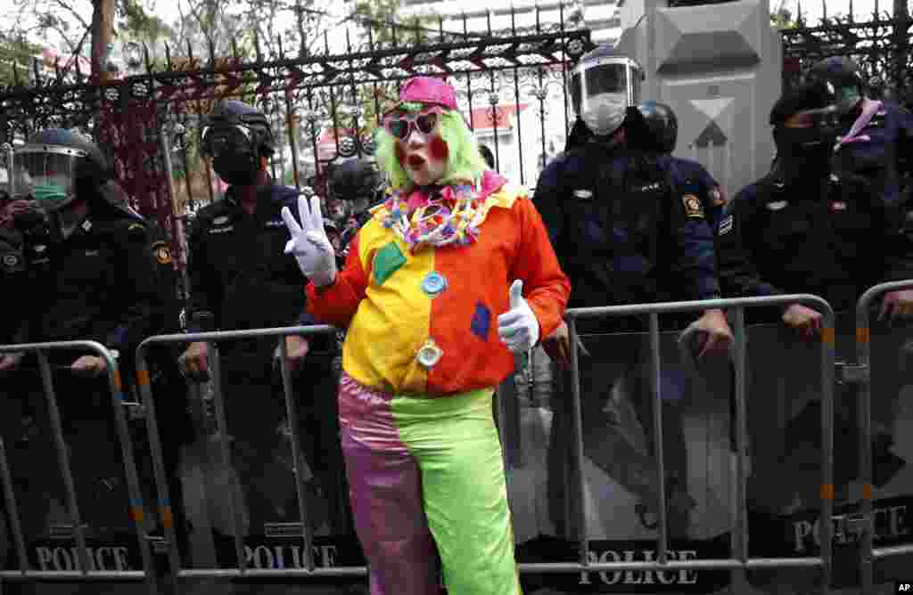 A pro-democracy protester wearing a clown costume raises a three-finger salute in front of riot police at Police Headquarter in Bangkok, Thailand.&nbsp;Protesters gathered to call for fairness for low-ranking police.