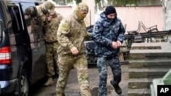 Un marin ukrainien (D), escorté par un agent des services de sécurité russes dans une salle d'audience à Simferopol, en Crimée, le 27 novembre 2018.