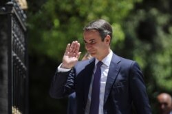 FILE - Greece's newly-elected prime minister Kyriakos Mitsotakis, waves as he walks shortly after his swearing-in ceremony at the Presidential Palace in Athens, July 8, 2019.