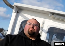 Lobsterman Drew Eaton, 27, stands aboard his boat in Stonington, Maine, Dec. 11, 2017.