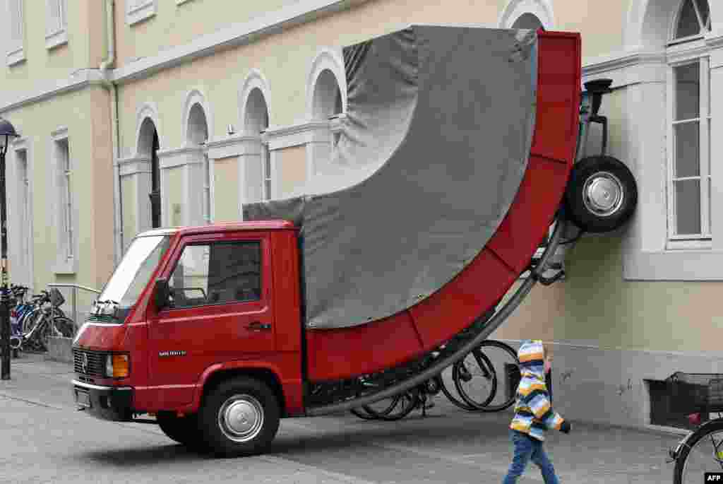 A child walks past the work &quot;Truck&quot; by Austrian artist Erwin Wurm in Karlsruhe, southwestern Germany. The work is part of the exhibition &quot;The City is the Star &ndash; Art at the Construction Site&quot; running across the city until Sep. 27, 2015.