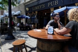 FILE - Diners are seated in an outdoor dining area on a sidewalk at Limey's Pub, in Norwood, Mass., June 18, 2020.