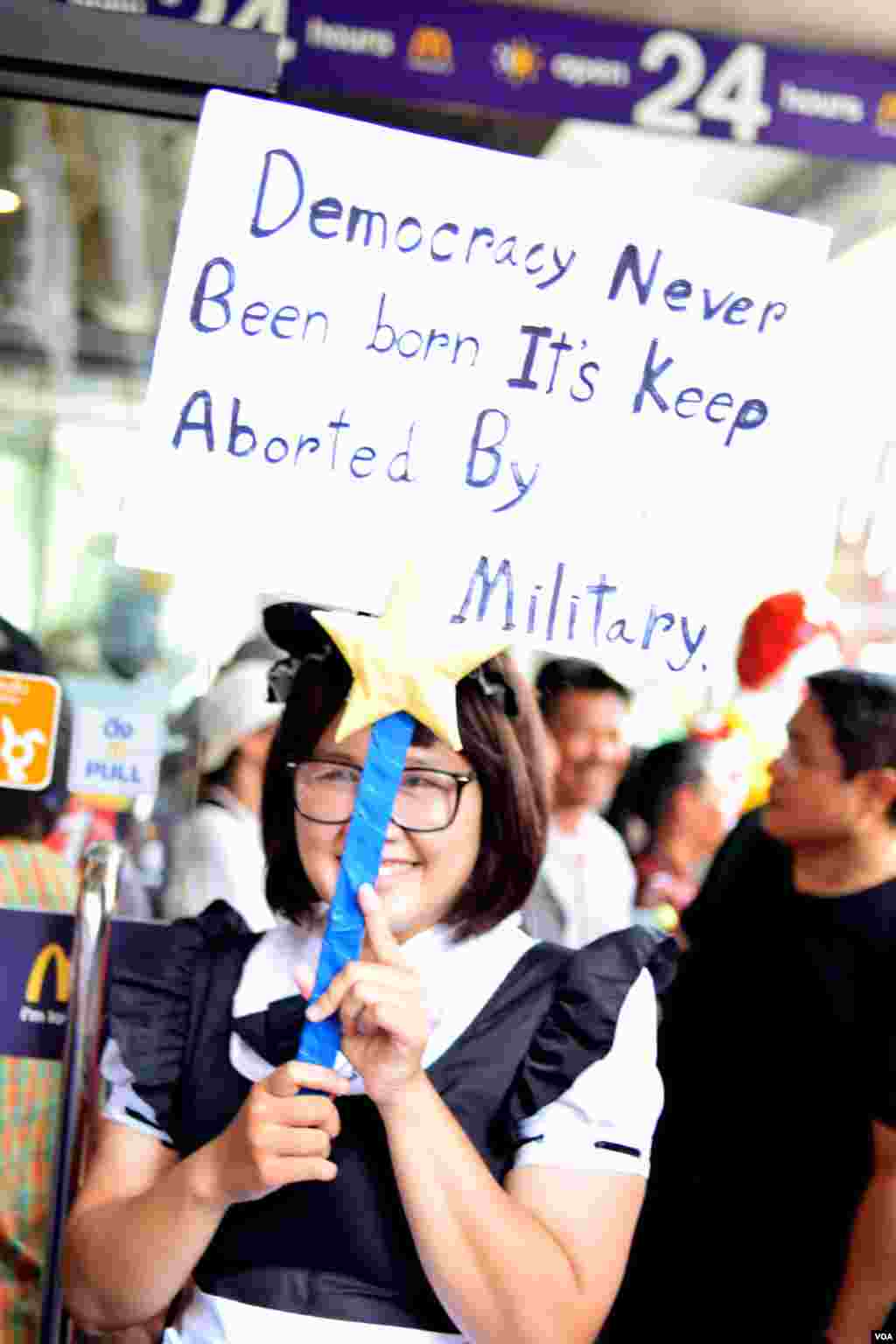 A anti-coup protester holds a banner at Amarin Plaza in central Bangkok, Thailand. (Steve Herman/VOA)