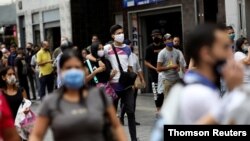 ARCHIVO - Ciudadanos con mascarillas sanitarias para protegerse de la COVID-19 caminan por Caracas, Venezuela.