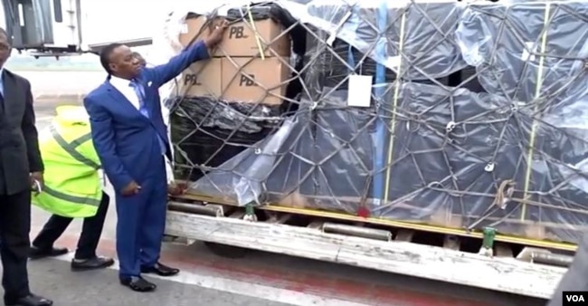 Cameroon's higher education minister, Jacques Fame Ndongo, takes receipt of a shipment of laptops at Yaounde-Nsimalen International Airport, Dec. 25, 2017. (M. Kindzeka/VOA)