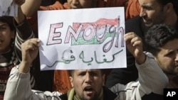 A Libyan protester holds up a sign against Libyan Leader Moammar Gadhafi during a demonstration, in Tobruk, Libya, February 23, 2011.