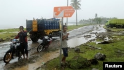 Beberapa pria di tengah hujan di kecamatan Sumur, Provinsi Banten, yang terdampak tsunami, 26 Desember 2018. (Foto: Reuters)