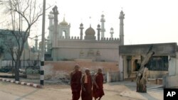 Tiga biksu Budha melintasi jalan di dekat sebuah masjid di Meikhtila, sekitar 550 kilometer sebelah utara Rangoon, Burma (Foto: dok). Kepolisian Burma telah menangkap sedikitnya 42 orang dan diperkirakan akan segera diadili dalam kekerasan sektarian di wilayah ini (4/4).