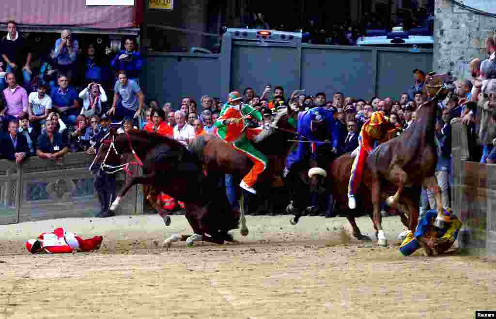 Jockeys fall off their horses during the Palio of Siena horse race, in Siena, Italy, Oct. 20, 2018.