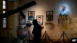 In this Friday, Feb. 1, 2019 photo, pictures of militiamen who died fighting the Islamic State group over the past four years and weapons are on display in the Popular Mobilization Forces War Museum on al-Mutanabi Street, Baghdad, Iraq. (AP Photo/Khalid M