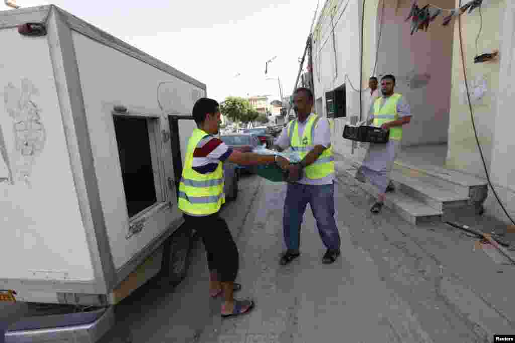 Orang-orang mengangkut makanan untuk berbuka puasa ke truk sepanjang bulan suci Islam di Tripoli, Libya, 30 Juni 2014.
