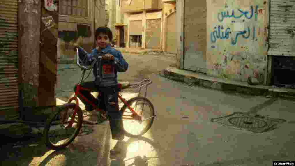 Yaseen on bicycle 30 minutes before a Syrian rocket from a government-held position exploded, killing he and his sister, Maryam, January 20, 2013 (Lens Young Homsi)