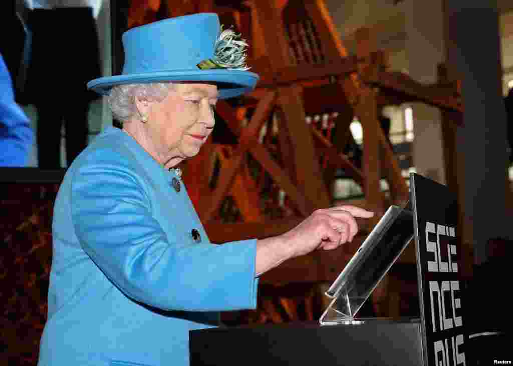 Britain&#39;s Queen Elizabeth presses a button to send her first Tweet during a visit to the &#39;Information Age&#39; Exhibition at the Science Museum in London. 