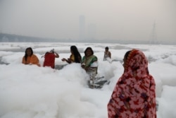 Para perempuan mandi di air sungai Yamuna yang tercemar di New Delhi, pada pagi yang berkabut, 8 November 2021. (REUTERS/Anushree Fadnavis)