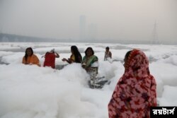 Para perempuan mandi di air sungai Yamuna yang tercemar di New Delhi, pada pagi yang berkabut, 8 November 2021. (REUTERS/Anushree Fadnavis)