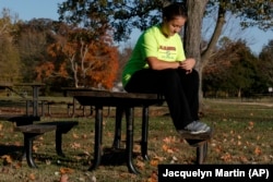Grace Brown, 14, adjusts her fitness tracker at the park where she does her jogging workouts for her "online PE" class, in Alexandria, Va., Friday, Nov. 1, 2019.
