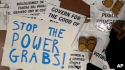 Carteles de protesta usados durante la sesión especial de la legislatura de Carolina del Norte en Raleigh, en la que se aprobaron medidas que restan poder al nuevo gobernador demócrata Roy Cooper.