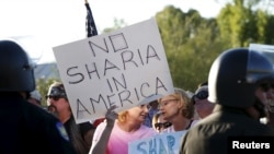 namoyishchilar qo'lidagi plakatda "Amerikada o'rin y'oq" deb yozilgan. Phoenix, Arizona, 2015-yil may