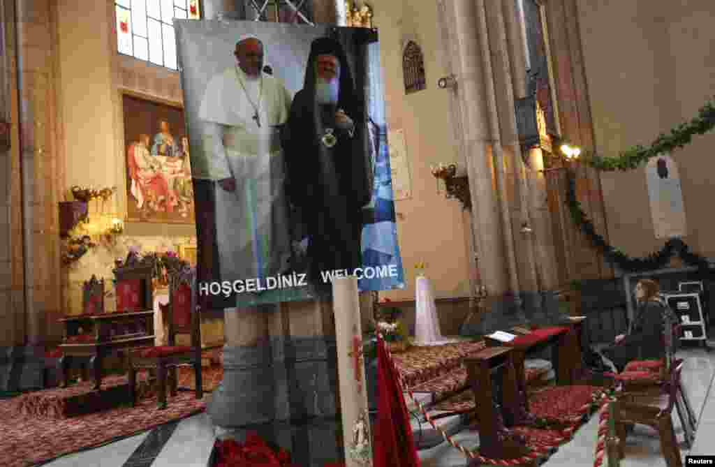 A woman prays near a poster with the pictures of Pope Francis, left, and Ecumenical Orthodox Patriarch Bartholomew I at St. Antuan Catholic church in central Istanbul, Nov. 28, 2014.