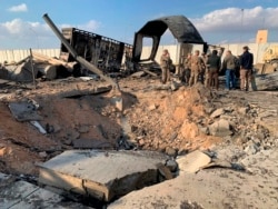 U.S. Soldiers and journalists stand near a crater caused by Iranian bombing at Ain al-Asad air base, in Anbar, Iraq, Jan. 13, 2020.