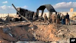 U.S. Soldiers and journalists stand near a crater caused by Iranian bombing at Ain al-Asad air base, in Anbar, Iraq, Jan. 13, 2020. 