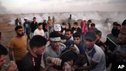 Palestinian protesters carry an injured man during a protest at the Gaza Strip's border with Israel, Friday, May 11, 2018. Gaza activists burned tires near the sealed border with Israel on Friday in a seventh weekly protest aimed at shaking off a decade-old blockade of their territory.