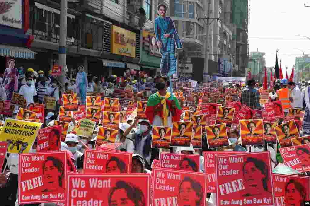 Anti-coup protesters hold up posters with images of deposed Myanmar leader Aung San Suu Kyi during a rally near the Mandalay Railway Station in Mandalay, Feb. 22, 2021.