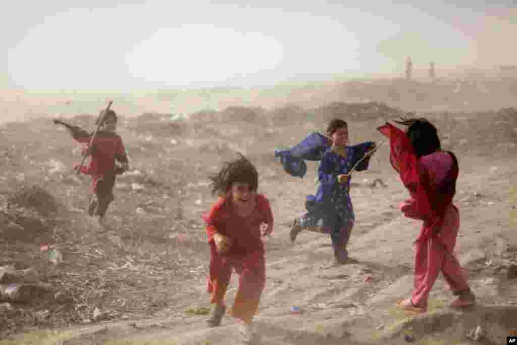 May 25: Pakistani girls get caught in a sand storm, in a slum on the outskirts of Islamabad, Pakistan. (AP Photo)