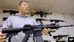 FILE - John Jackson, co-owner of Capitol City Arms Supply shows off an AR-15 assault rifle for sale at his business in Springfield, Illinois, Jan. 16, 2013.