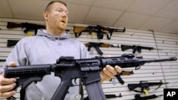 Ông John Jackson, đồng sở hữu cửa hàng vũ khí Capitol City ở Springfield, Illinois, đưa ra một khẩu súng trường tấn công AR-15 để bán, ngày 16 tháng 1 năm 2013.