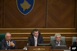 FILE - Speaker of the parliament Kadri Veseli, center, addresses Kosovo lawmakers during debate on passing constitutional amendments that would allow the establishment of a special court to prosecute its top leaders and former guerrilla fighters for war crimes, in Pristina, Aug. 3, 2015.
