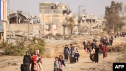 FILE — Palestinians fleeing the north walk along the Salaheddine road in the Zeitoun district on the southern outskirts of Gaza City on November 26, 2023.